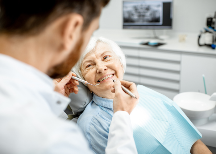 Behandlerin kontrolliert die neuen festen Zähne einer Patientin